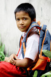 Portrait of cute boy with backpack sitting outdoors