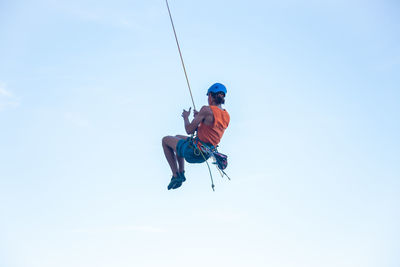 Low angle view of man paragliding against sky