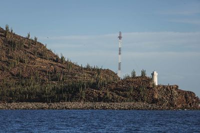 Lighthouse by sea against sky