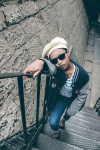 Portrait of man wearing sunglasses standing against brick wall