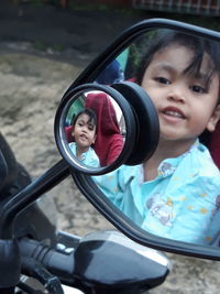 Reflection of smiling girl in motorcycle mirror