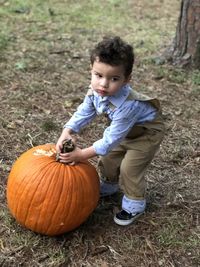 Portrait of boy holding pumpkin while standing on land