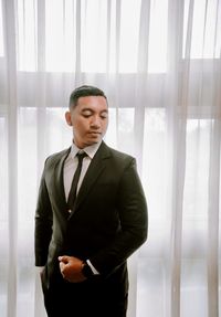 Portrait of businessman standing against window at home