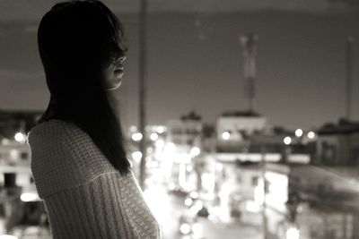 Woman looking at illuminated city at night