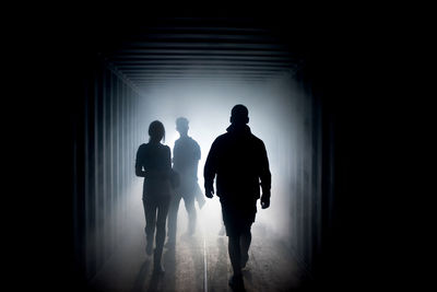 Rear view of silhouette people walking in tunnel