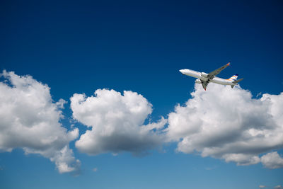 Low angle view of airplane flying against blue sky