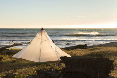 White tent on beach against clear sky during sunset