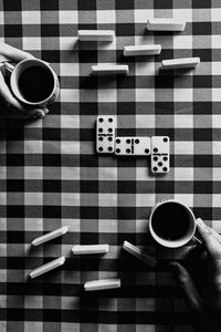 High angle view of hands with coffee in cup on table