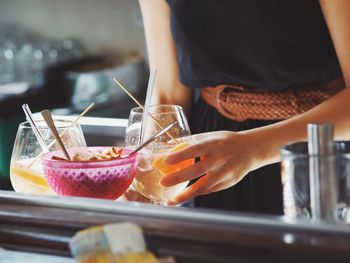 Midsection of waitress serving food and drinks on restaurant table