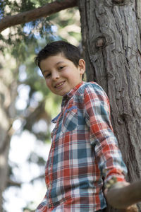 Portrait of smiling boy standing against tree