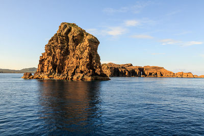 Rock formation by sea against blue sky