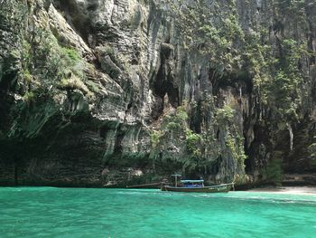 Longtail boat moored on sea by mountain