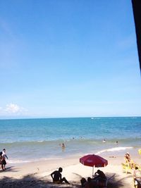 People playing on beach against blue sky