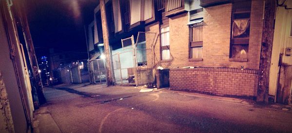 Empty alley amidst buildings in city at night