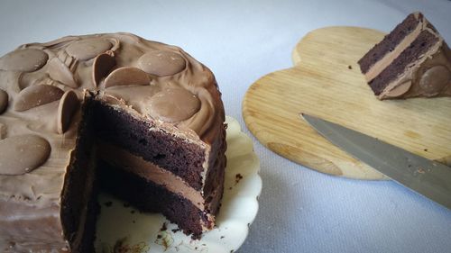 High angle view of chocolate cake in plate with slice and knife on table