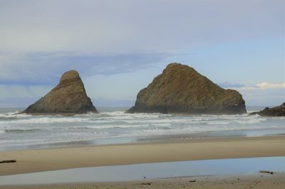 Rock formation on beach against sky
