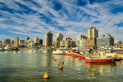 Boats in sea by cityscape against sky