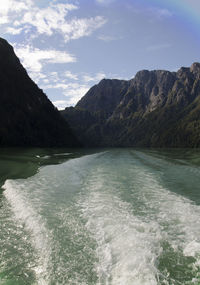 Scenic view of sea by mountains against sky