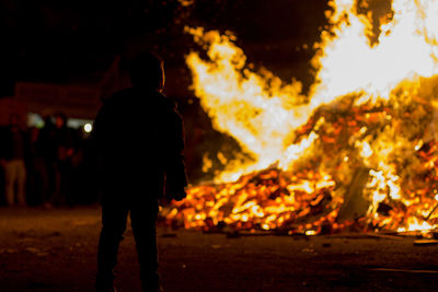 Silhouette man standing by bonfire at night