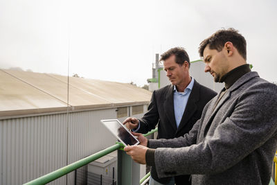 Businessmen discussing over tablet pc at recycling plant