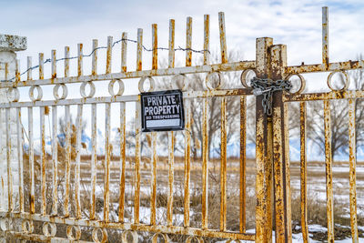 Information sign by fence on field against sky