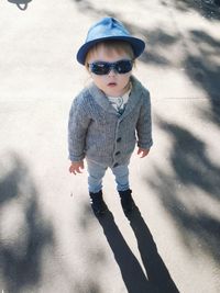 Sunlight falling on boy wearing hat and sunglasses while standing on footpath