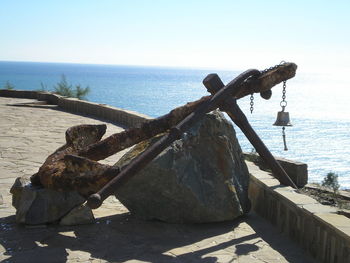 Close-up of rusty metal on beach against clear sky