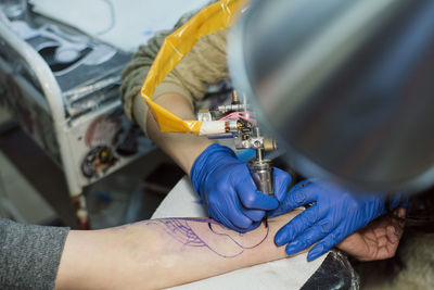 High angle view of artist making tattoo on customer hand