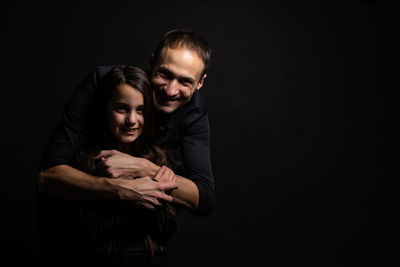 Young dad with a cute emotional daughter on a dark background. place for your text.