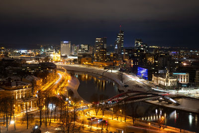 High angle view of illuminated buildings by river at night