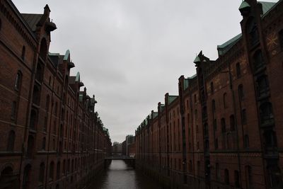 Canal amidst buildings in city against sky