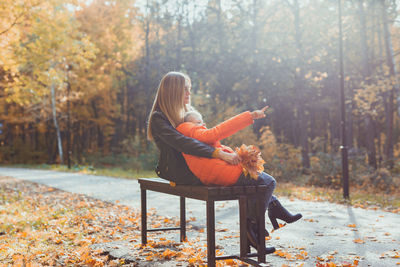 Woman sitting on sidewalk during autumn