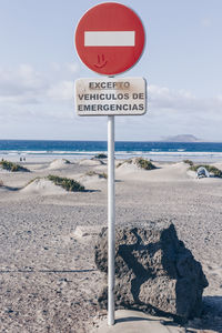 Information sign on road by sea against sky