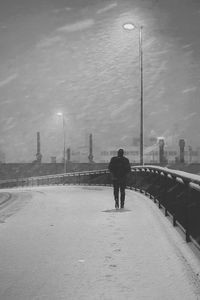 Rear view of man walking on street during winter