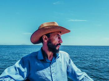 Man wearing hat while looking at sea against sky