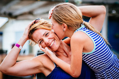 Portrait of a smiling young woman and mother  getting a koss from her daughter. 