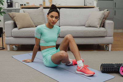 Young woman exercising on sofa at home