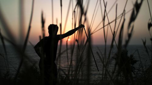 Silhouette man standing at beach during sunset