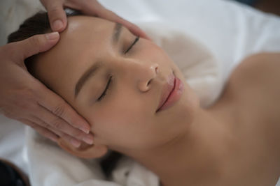 Cropped hands of therapist massaging young woman in spa