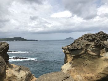 Scenic view of rock formation by sea against sky