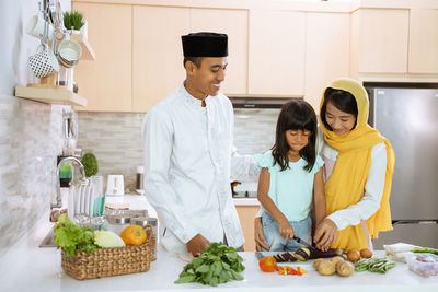 People standing by food in kitchen