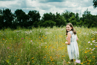 Teen girl smiling looking over her shoulder in a field of wild flowers