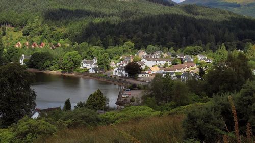 High angle view of river amidst trees and houses against sky