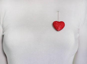 Close-up of woman with heart shape over white background