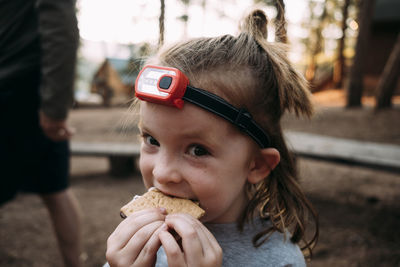 Close-up portrait of cute girl eating sweet food while standing in forest