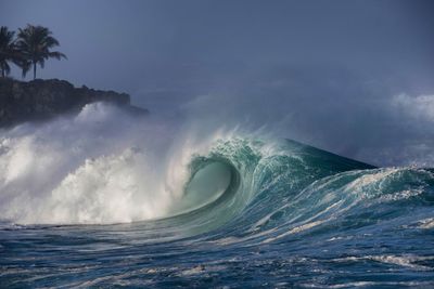 Waves splashing on sea against sky