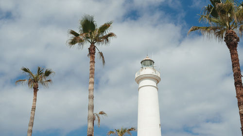 White tower lighthouse between the tree palms in sicily daylight