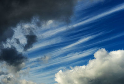 Low angle view of sunlight streaming through clouds