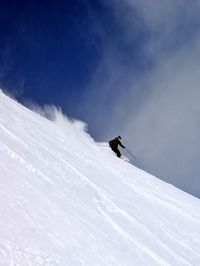 Person skiing on snow covered slope against sky