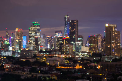 Illuminated buildings in city against sky at night